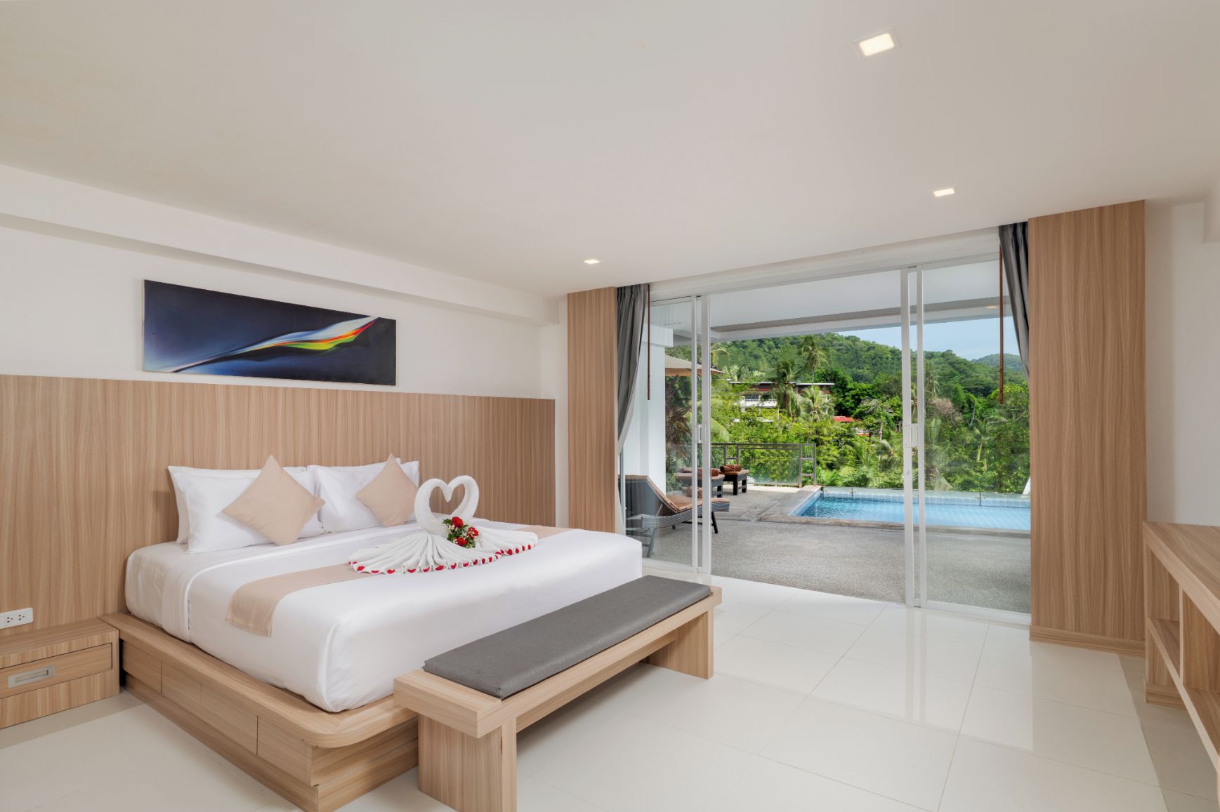 Ein modernes Hotelzimmer mit einem großen Bett, einer Bank, Blick auf einen Pool und einem Balkon mit schöner Aussicht.