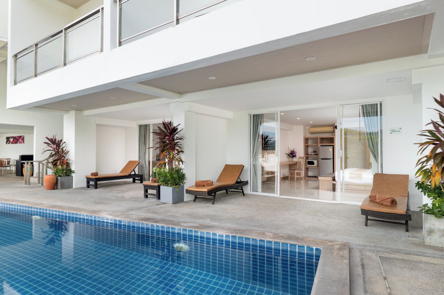 A modern indoor pool area with lounge chairs and potted plants.
