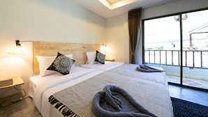 Habitación de hotel con una cama grande, dos mesitas de noche y vistas a través de un ventanal corredero.