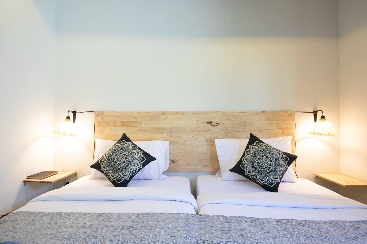 A double bed with a wooden headboard, two bedside tables with lamps, and decorative pillows.