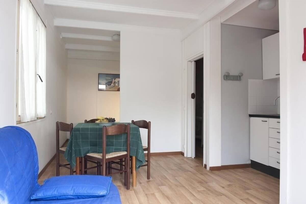 A dining area with a table and chairs, a blue couch, and a kitchen area with cabinets.