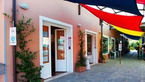 A building with multiple doors, some open, and a covered walkway with a colorful canopy. - New Camping Le Tamerici (Cecina)