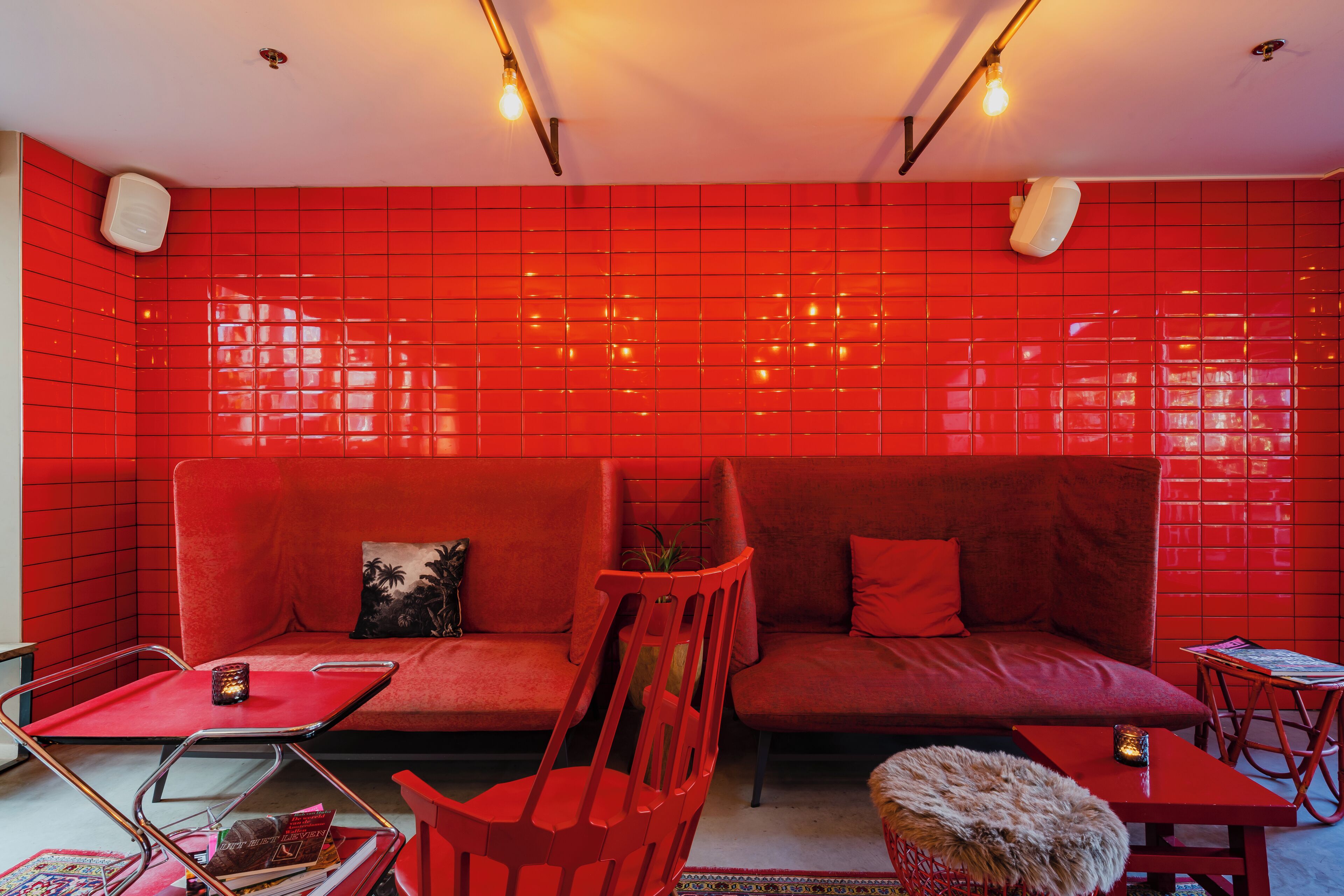 A red-tiled room with a sofa, a chair, a small table, and a floor lamp.