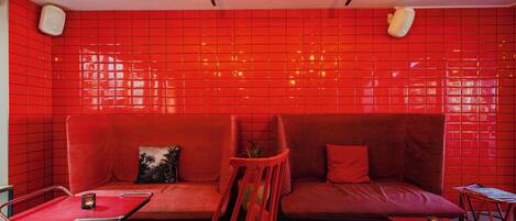 A red-tiled room with a sofa, a chair, a small table, and a floor lamp.