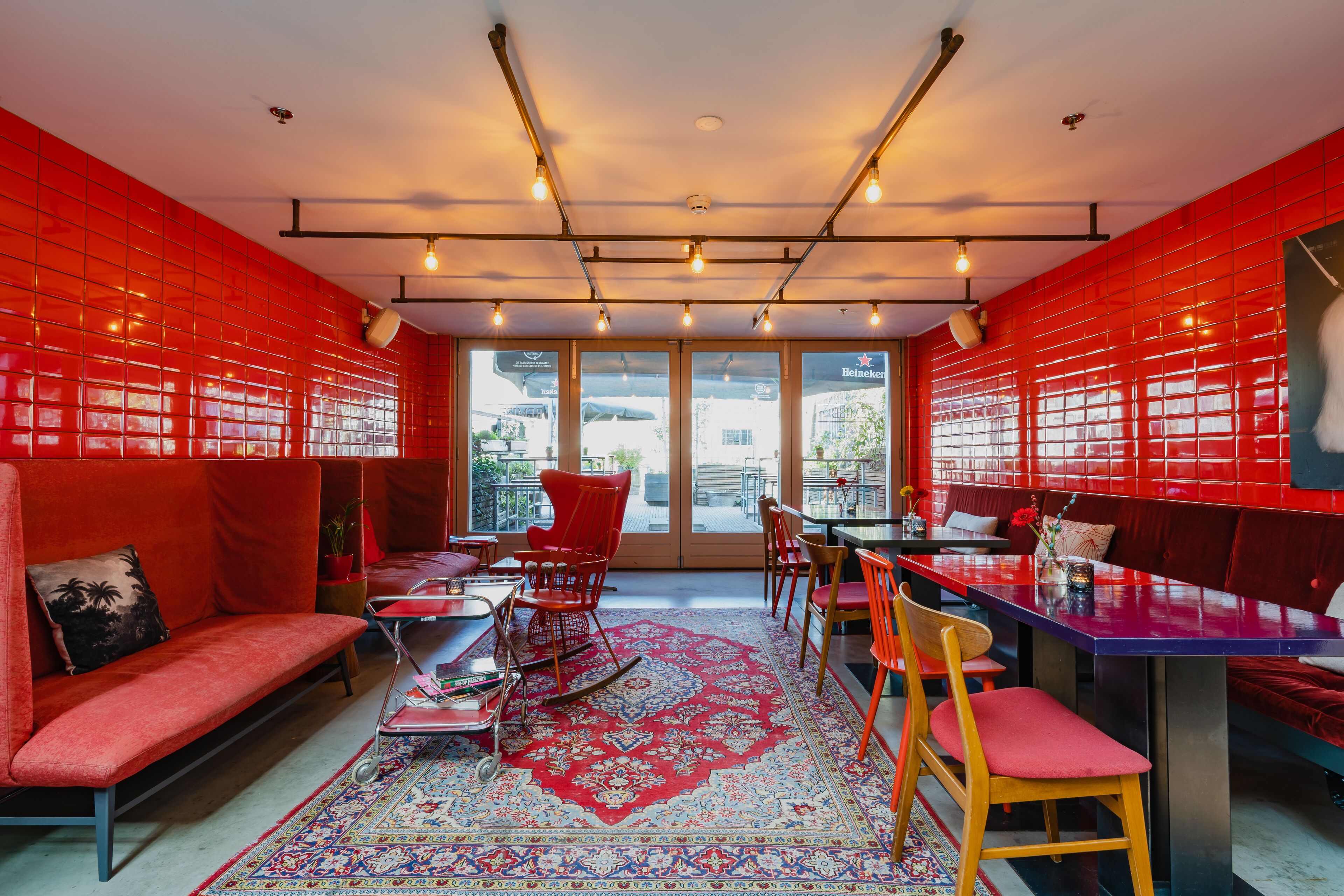 Un intérieur moderne avec des murs rouges, une grande fenêtre et un coin salon comprenant un canapé rouge et des fauteuils.
