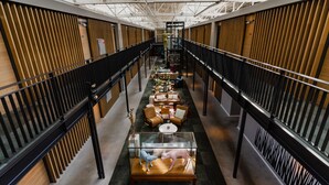 A spacious atrium with a central seating area, a glass display case with sculptures, and a high ceiling with skylights. - Hotel De Hallen (Amsterdam)