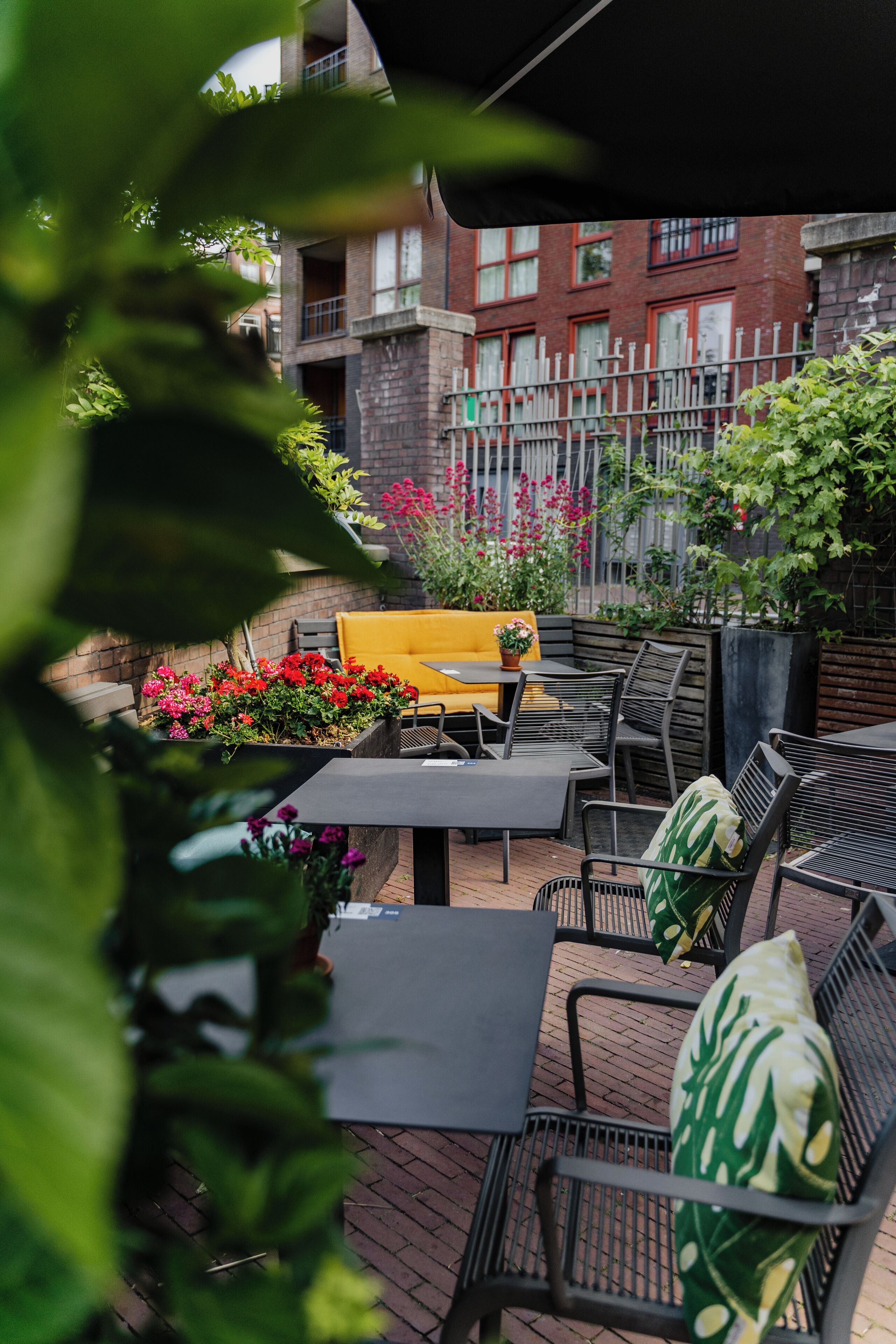 An outdoor seating area with tables and chairs, surrounded by potted plants and flowers.