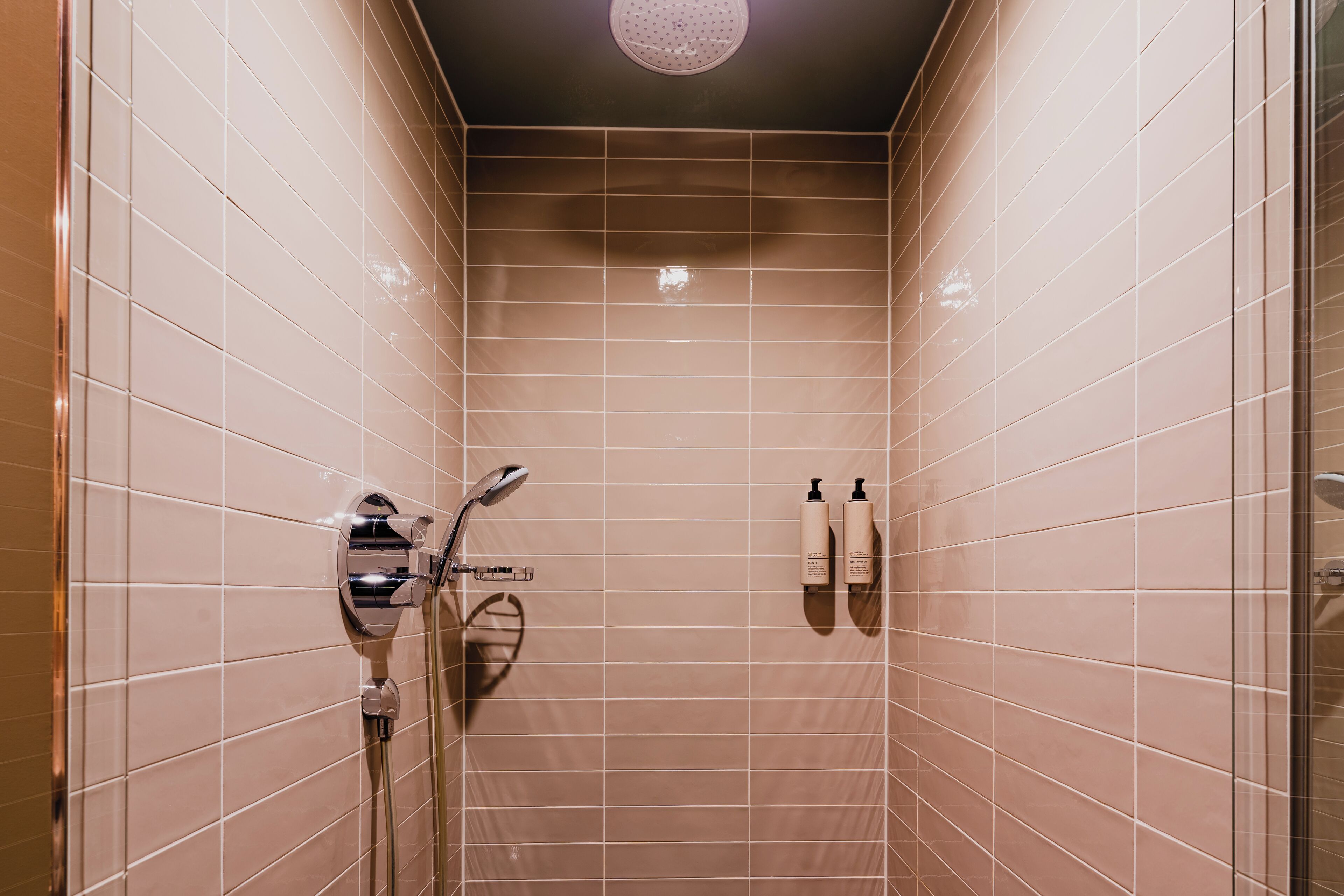 A shower with a handheld showerhead and a wall-mounted faucet.