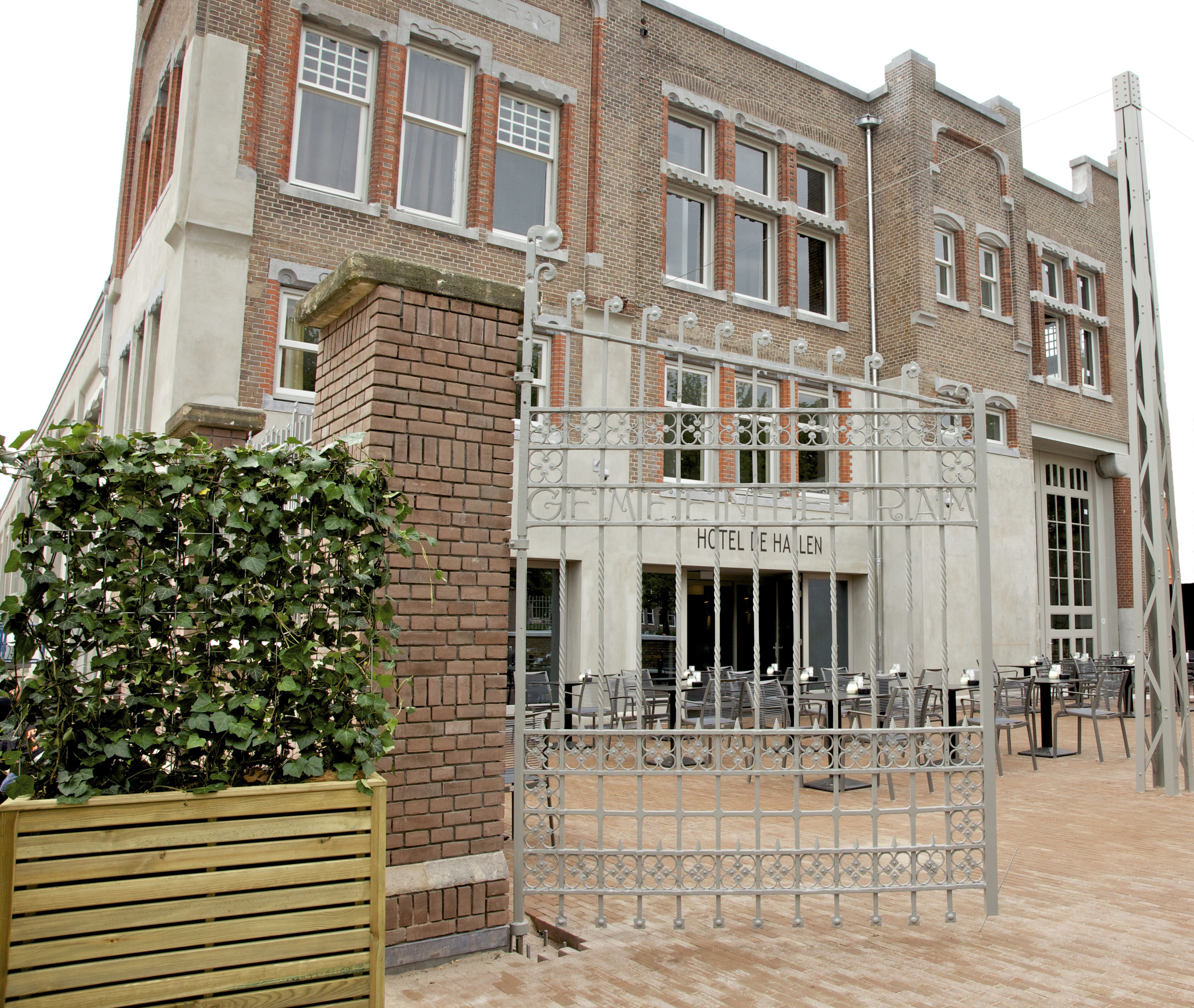 A hotel entrance with a wrought iron gate, brick facade, and outdoor seating area.