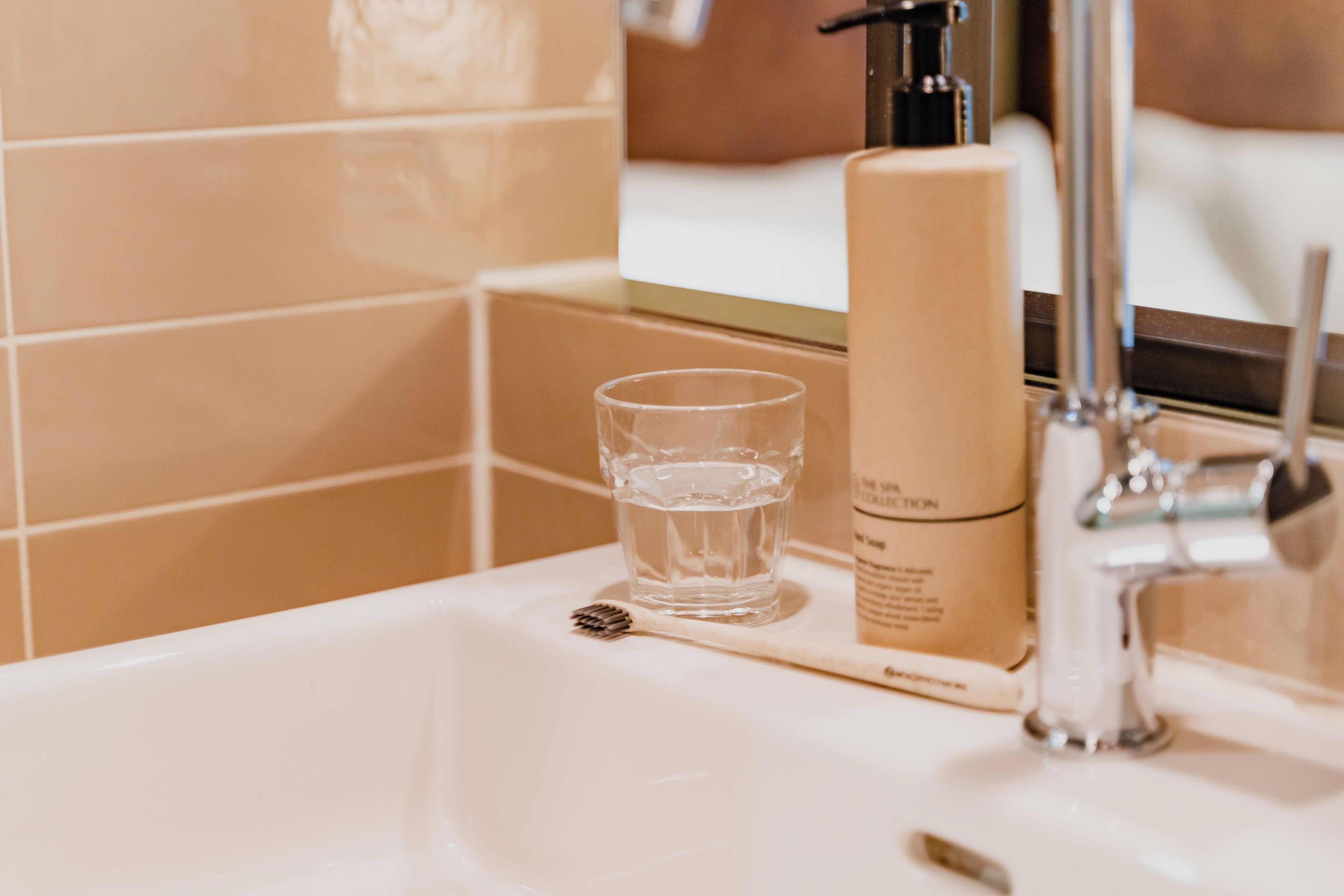 Un lavabo de salle de bain avec une brosse à dents, un verre d’eau et un flacon de savon.