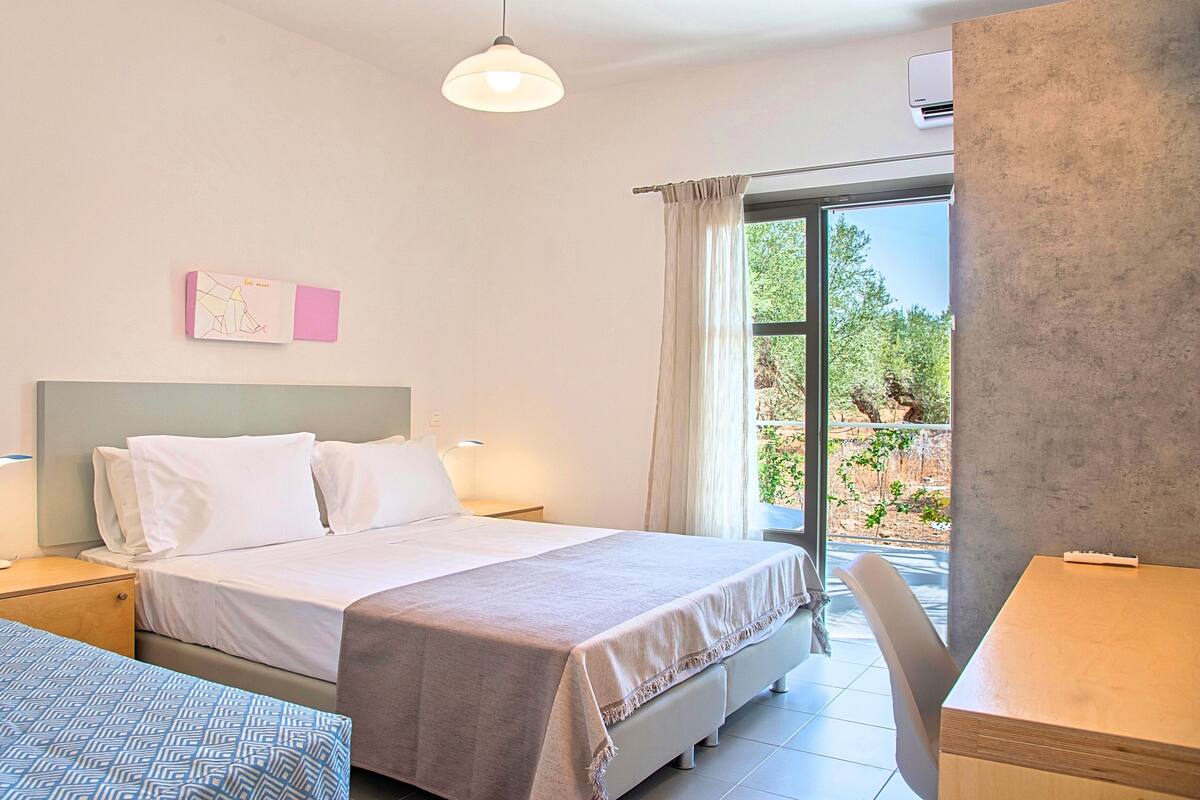 Een hotelkamer met een bed, nachtkastje, lamp en uitzicht op het omliggende landschap.