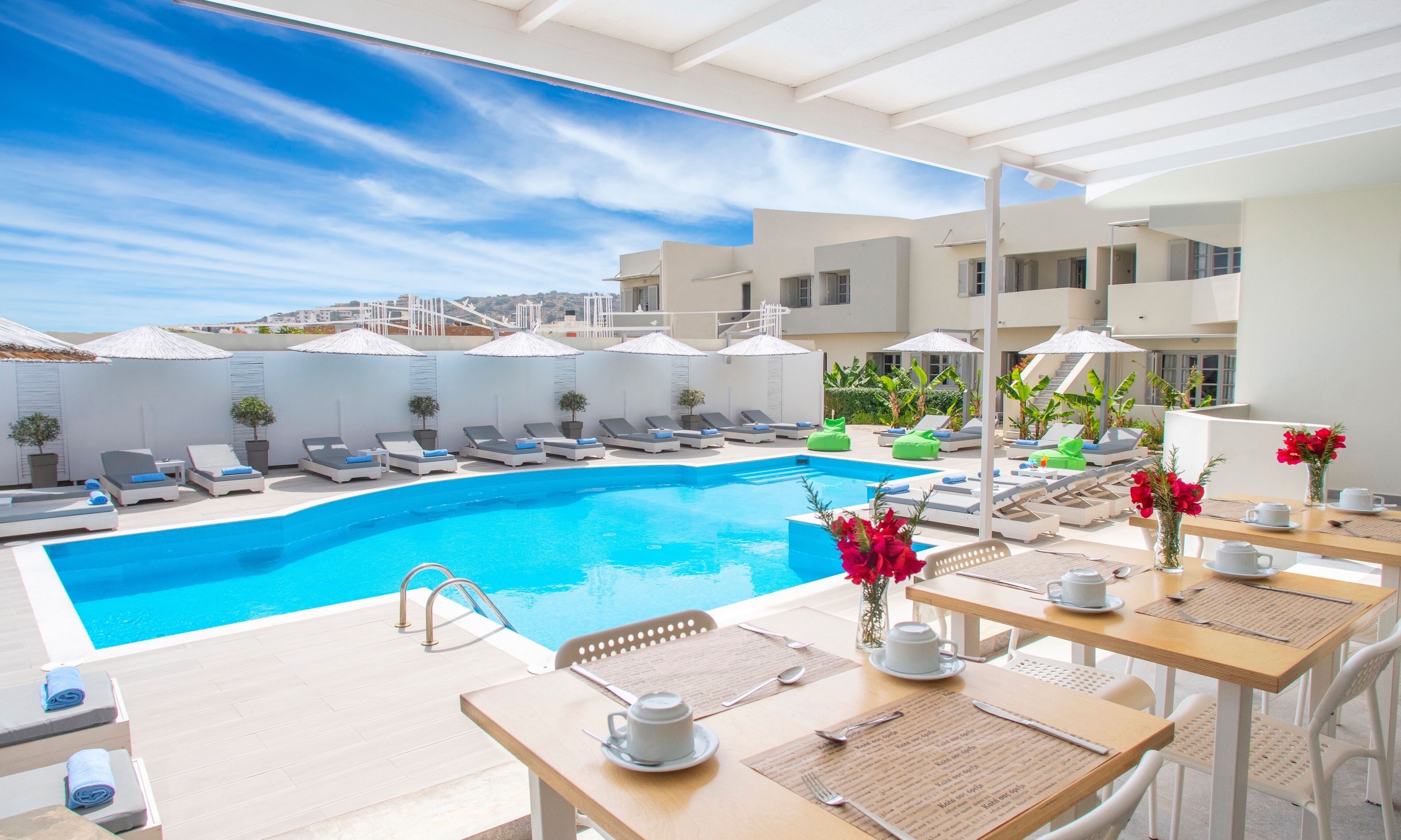 Un área junto a la piscina con tumbonas, piscina y mobiliario exterior con mesas y sillas.