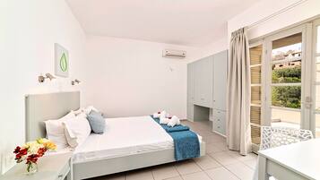 A hotel room with a bed, a nightstand with a vase of flowers, a wardrobe, and a balcony with a view.