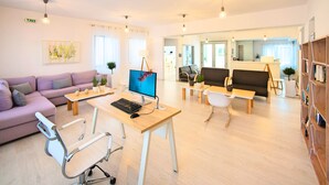 Un espacio de oficina moderno con escritorio, computadora, silla de oficina, sofá y estantería.