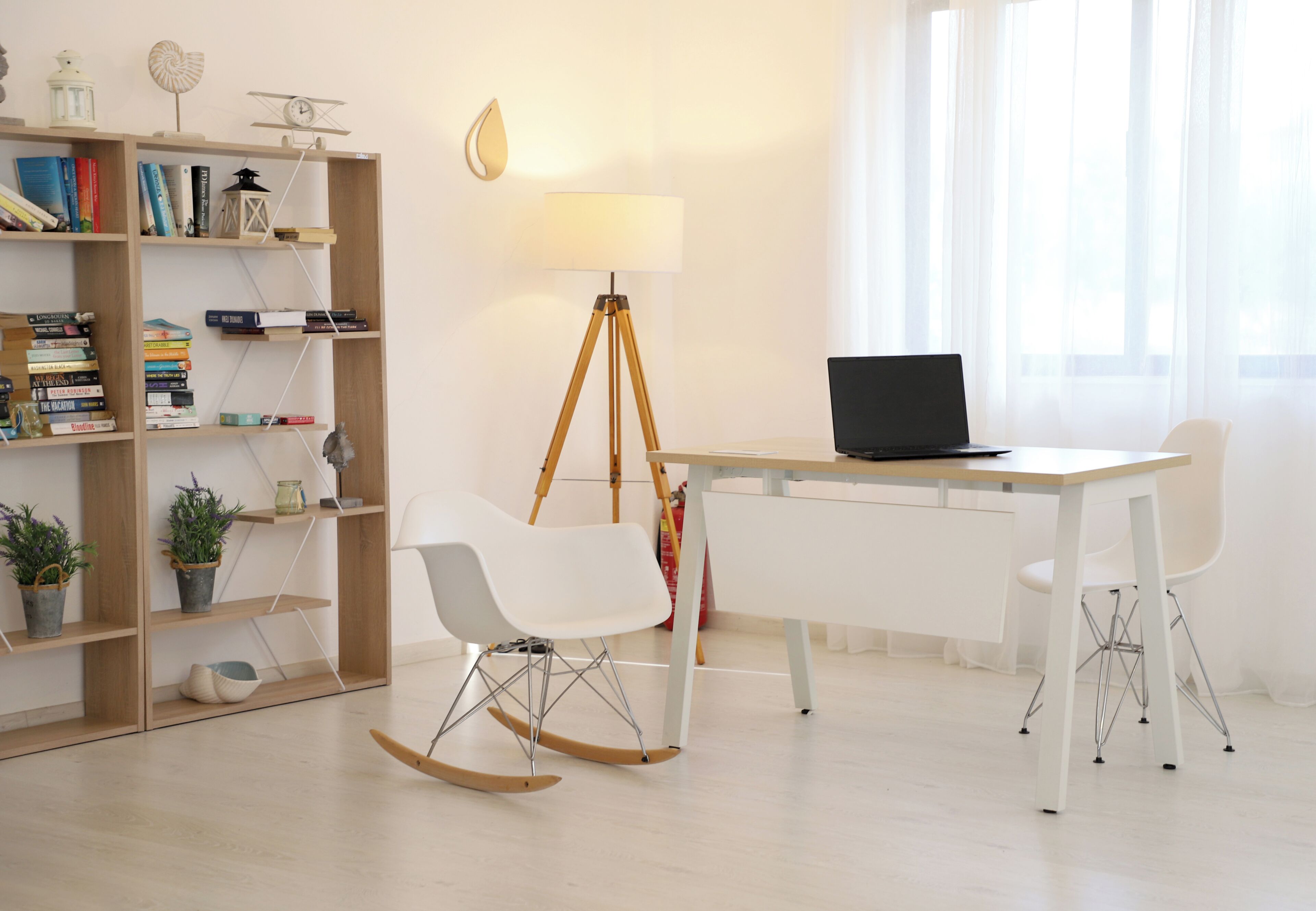 A modern room with a desk, two white chairs, a bookshelf, a lamp, and a rocking chair.