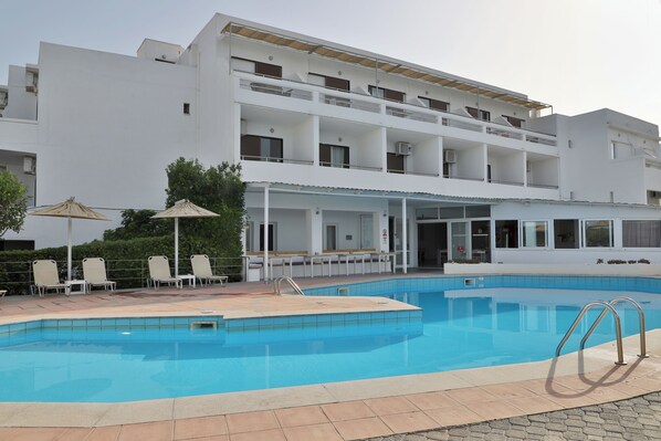 Un hotel moderno con piscina, zona de estar al aire libre y terraza cubierta.
