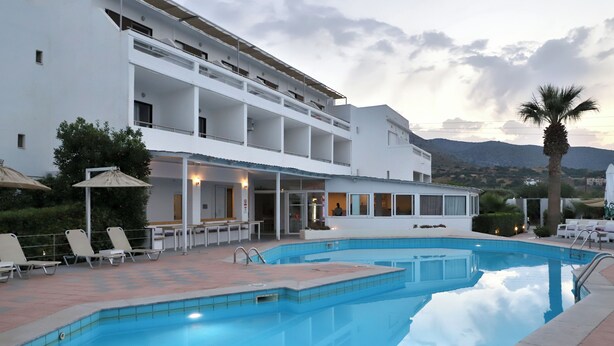 Zona de piscina con sillones de descanso y un edificio con balcones.