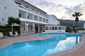 Zona de piscina con sillones de descanso y un edificio con balcones.