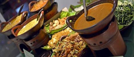 A variety of dishes displayed in traditional clay pots on a table, with a sign indicating 'Nasi Pecel' and 'Yu Sreep'.