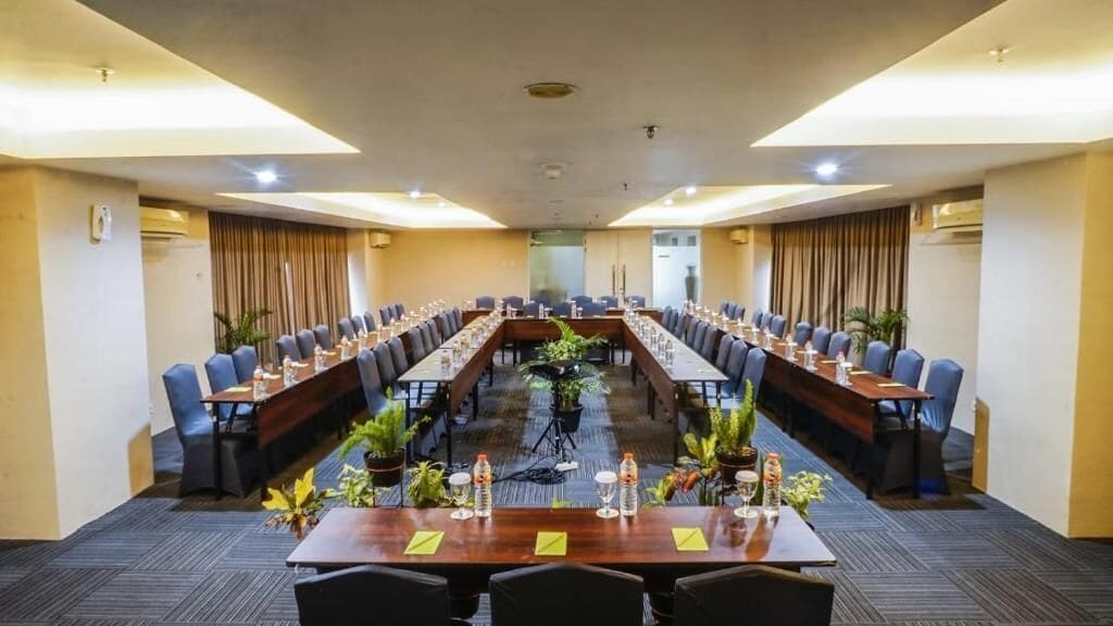 A conference room with a long table, multiple chairs, and potted plants.