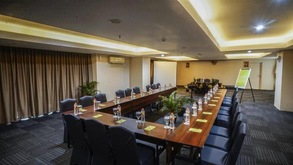 Une salle de conférence équipée d’une longue table, de chaises et d’un présentoir pour tableau mobile.