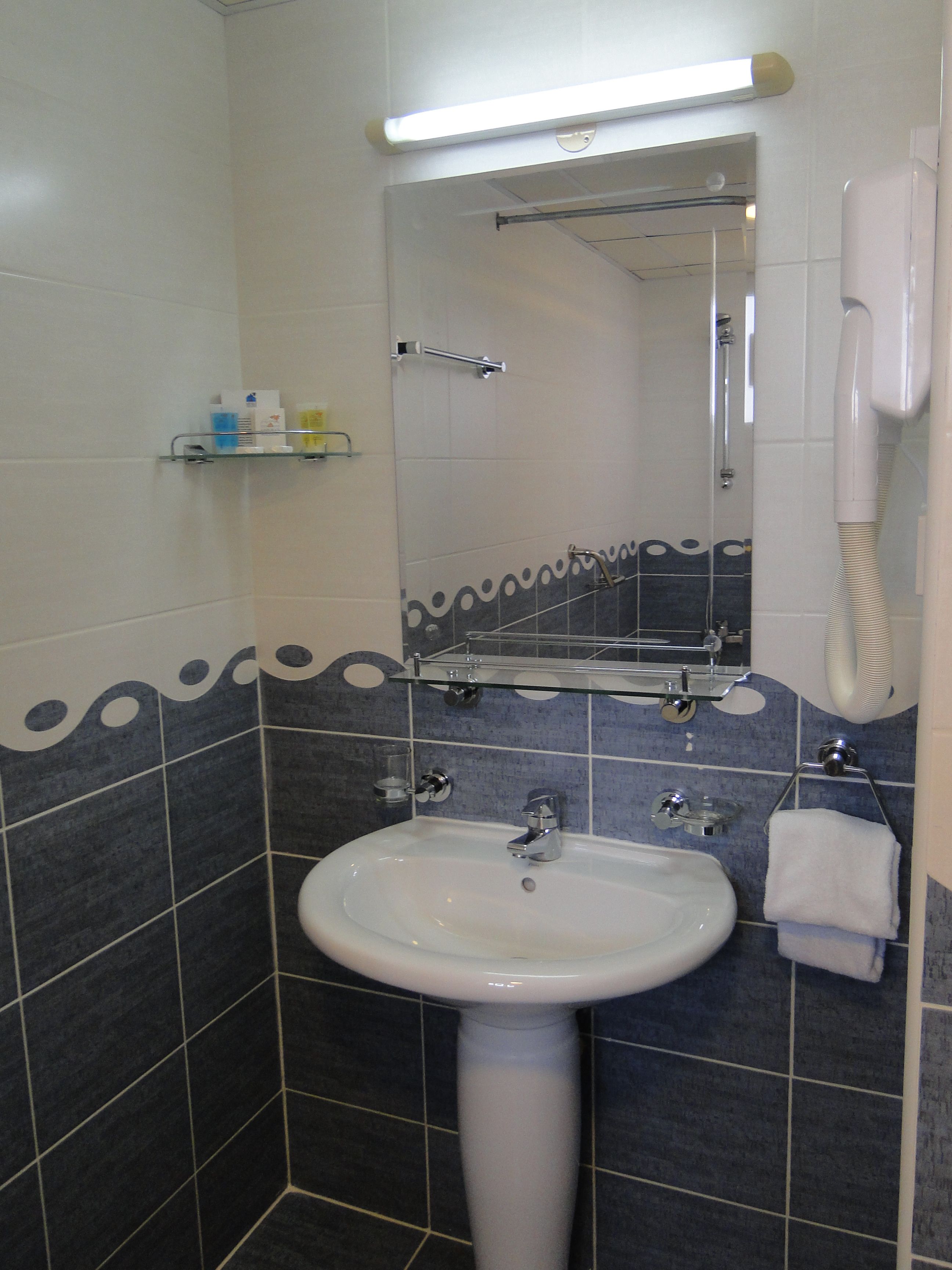 A bathroom with a white sink, a mirror, a towel rack, and a hand dryer.