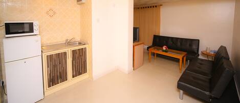 A compact living space with a kitchenette, a sofa, and a small table.