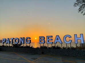 A sunset view with the words "PATONG BEACH" illuminated in the foreground. - Lemongrass Hotel (Patong)