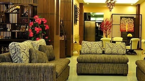 A living room with a sofa set, a coffee table, and a decorative wall piece. - Lemongrass Hotel (Patong)