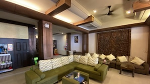 A modern living room with a sectional sofa, a coffee table, and a decorative wall panel. - Lemongrass Hotel (Patong)