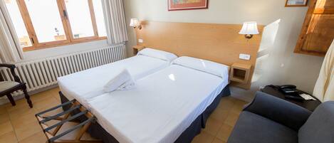 Une chambre d’hôtel avec un grand lit, une chaise, un canapé, un bureau avec un téléphone et une fenêtre avec des rideaux.