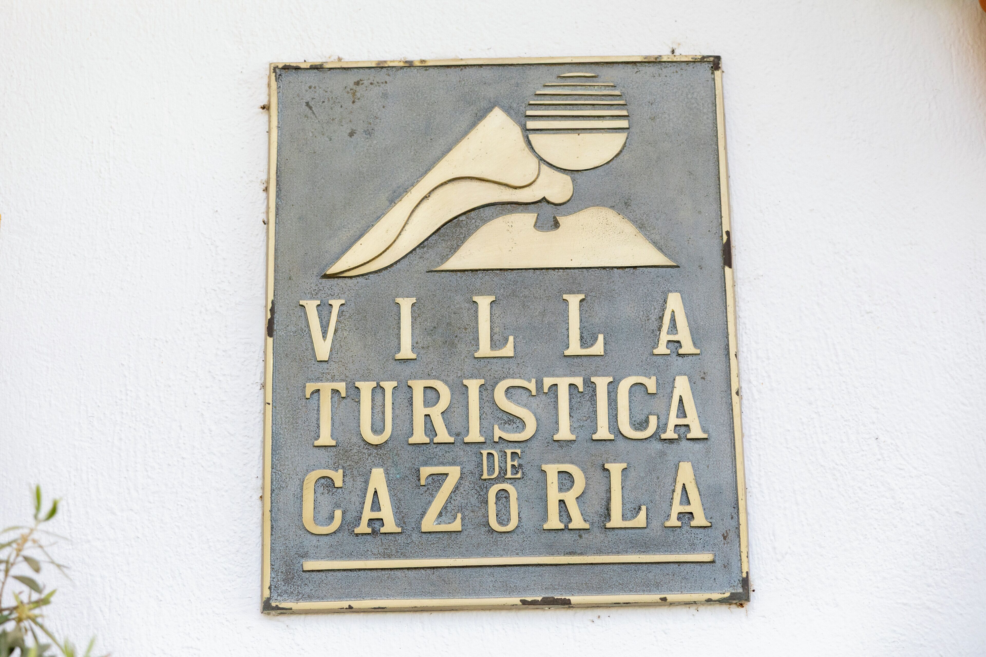 Un letrero con el texto 'VILLA TURISTICA DE CAZORLA' y un diseño estilizado de un ave.