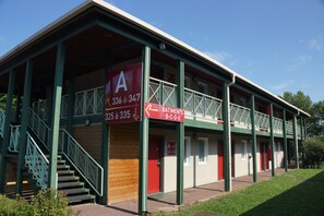 A two-story building with a red and white color scheme, featuring a staircase and multiple doors. - Brit Hotel Confort Lyon Dardilly (Dardilly)