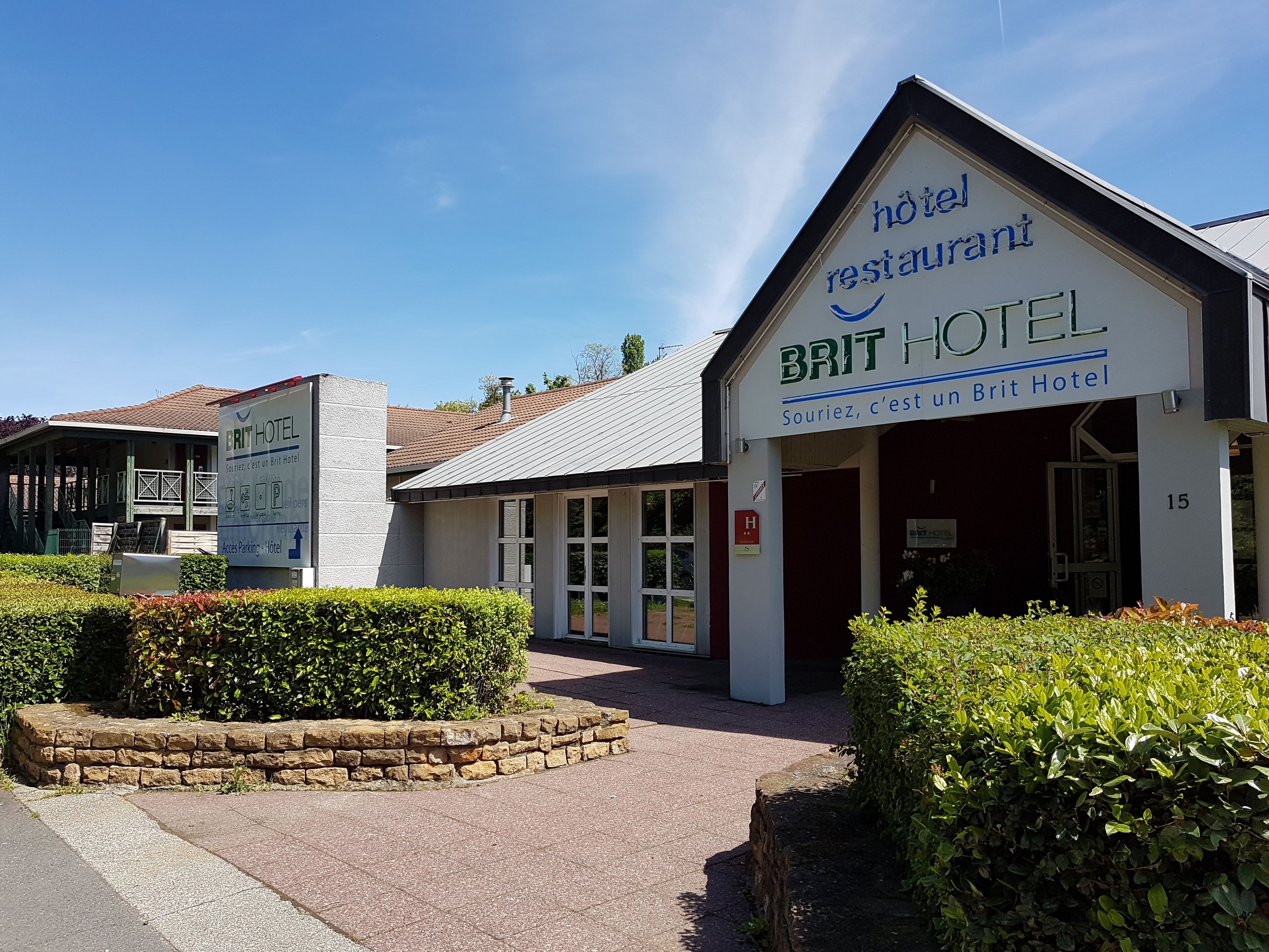 A Brit Hotel with a sign indicating it is a hotel and restaurant. There is a parking sign and a wheelchair accessibility symbol.