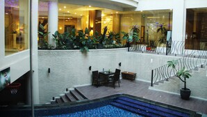 A hotel lobby with a pool area, seating, and a staircase.
