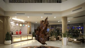 A lobby with a reception desk, a large abstract sculpture, and a seating area with multiple chairs and a coffee table.