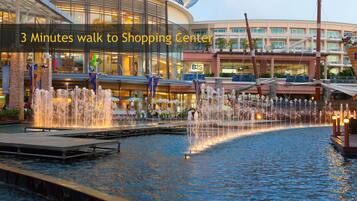 A shopping center with a water fountain and a building with multiple levels and balconies.