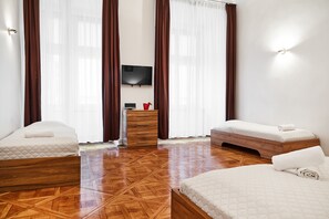 A hotel room with two beds, a wooden dresser, a flat-screen TV, and a large window with curtains. - Krakow For You Budget (Kraków)