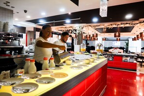 A buffet setup with a counter, plates, and various food items. - Hotel Benetússer (Benetusser)