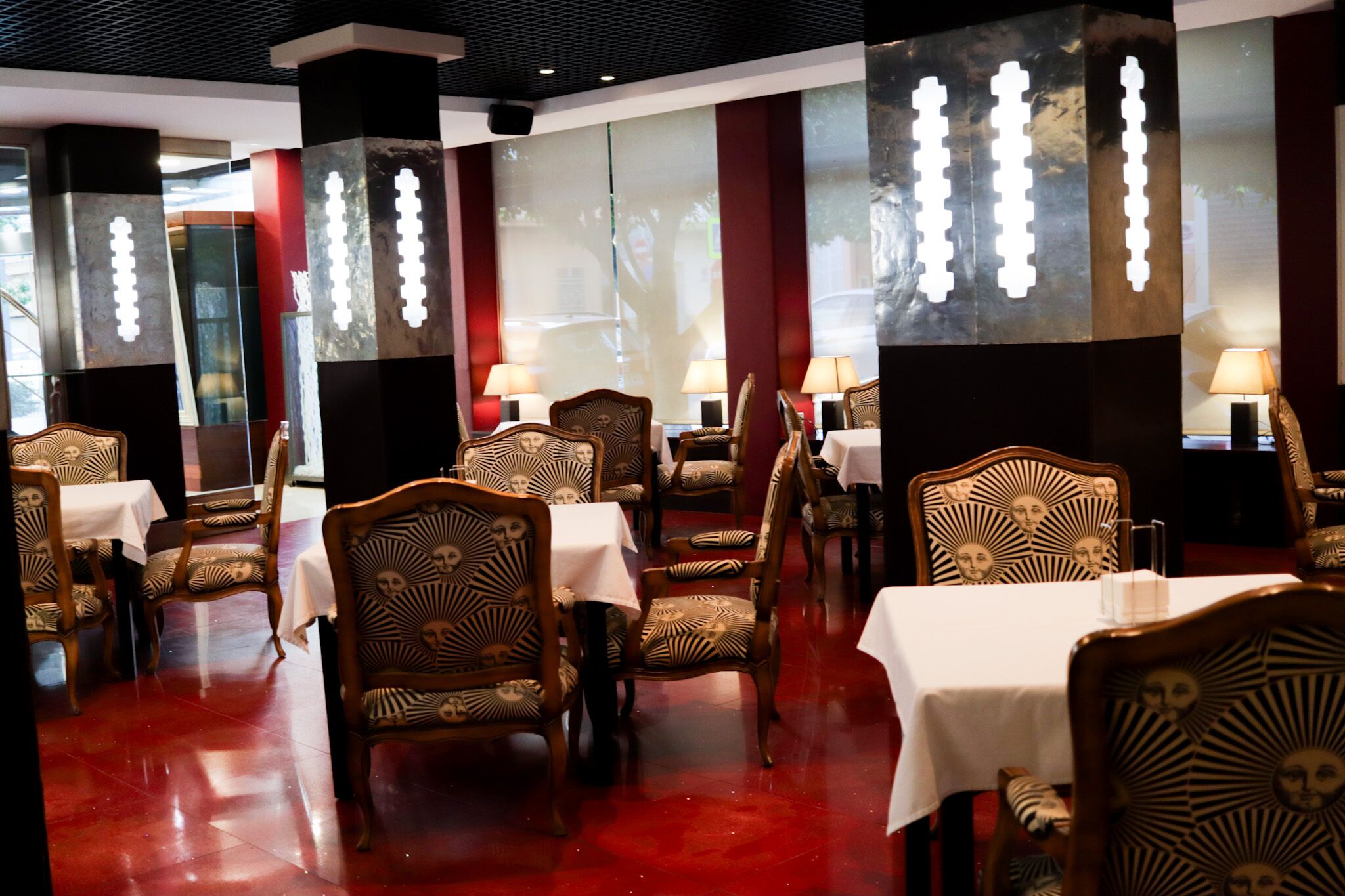 Een restaurant met houten stoelen en tafels, rode vloer en decoratieve wandpanelen.