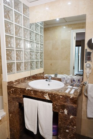 A bathroom with a marble sink, glass block window, and a hairdryer on the counter. - Hotel Benetússer (Benetusser)