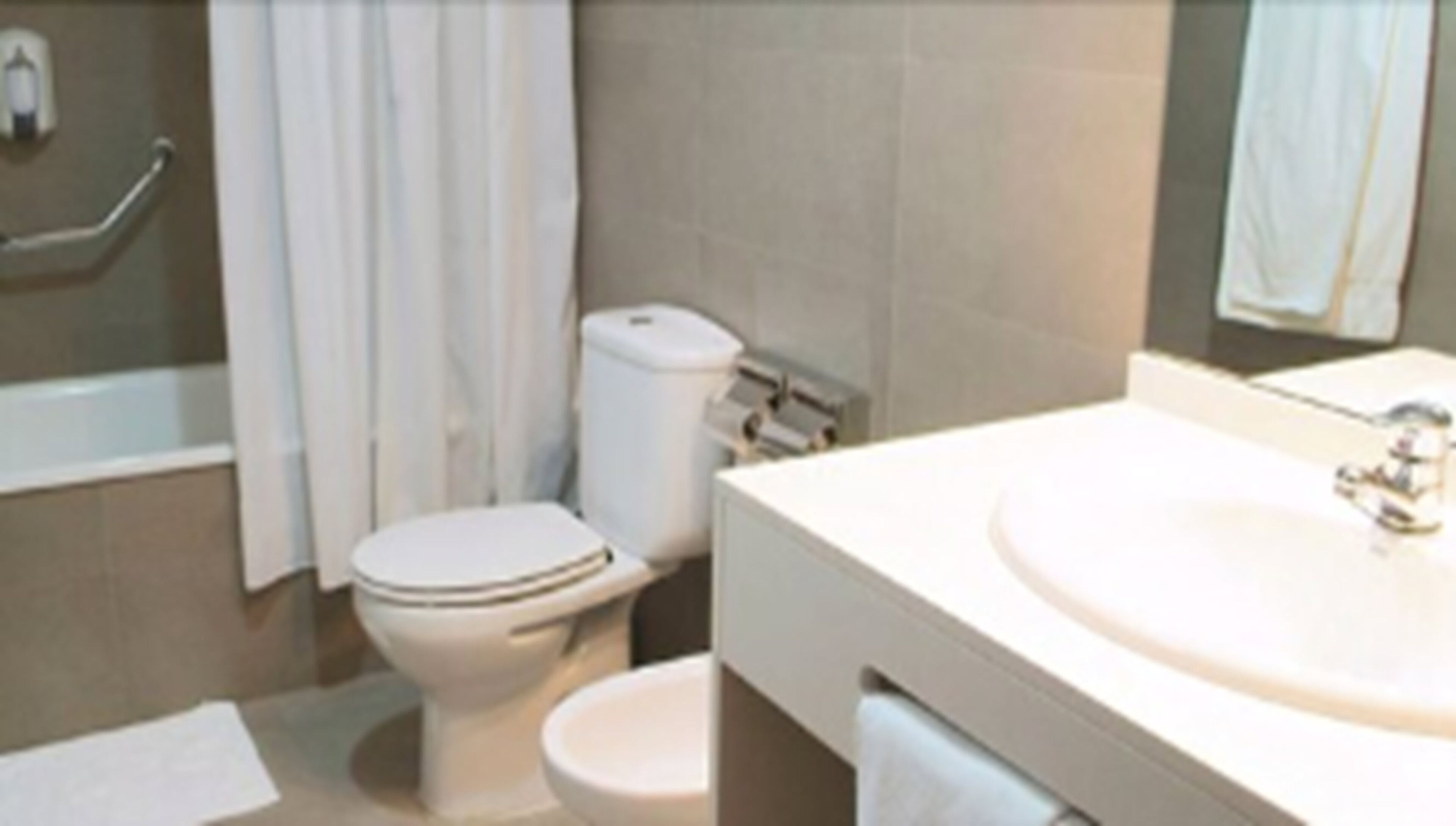 A bathroom with a toilet, bidet, and a sink.