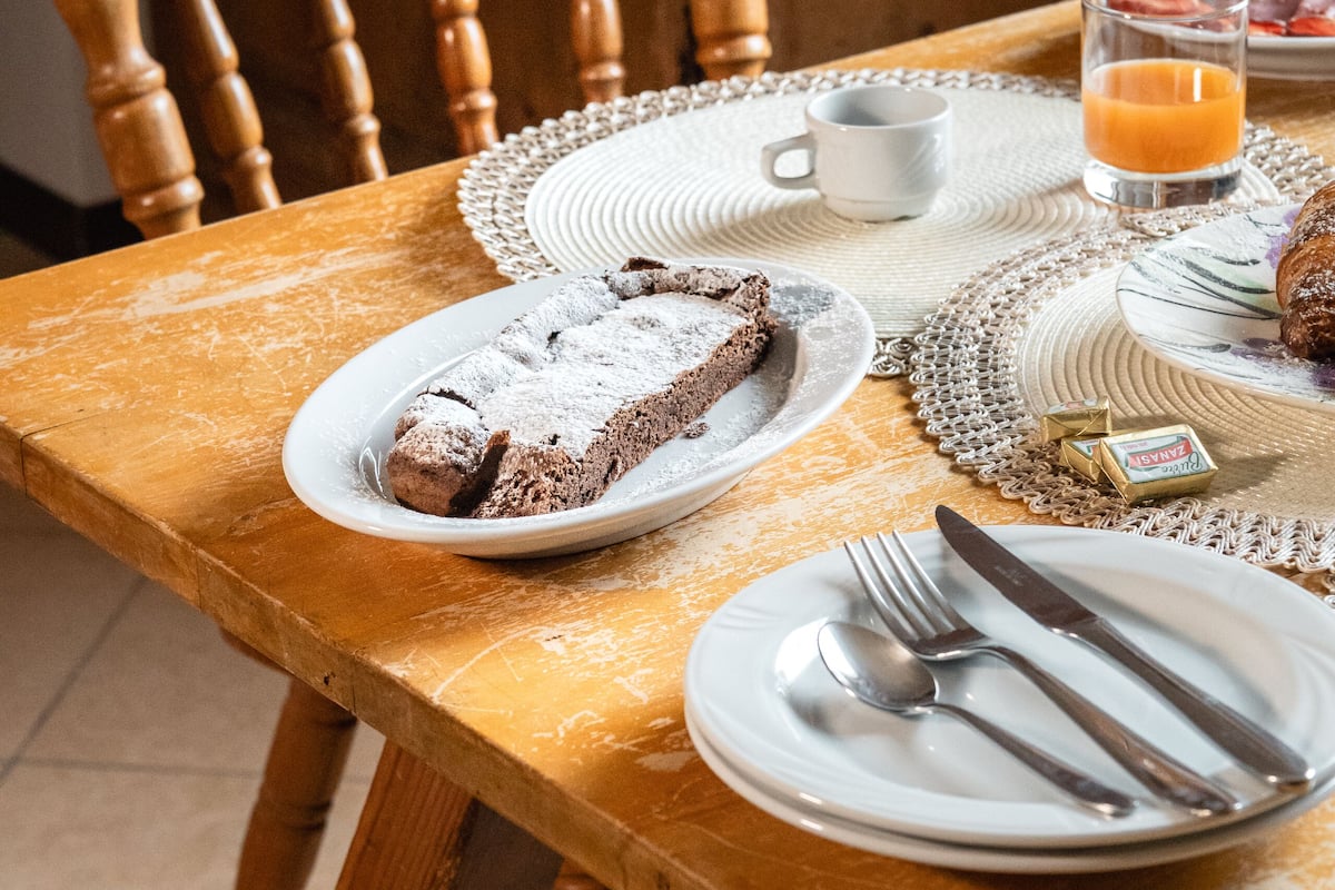 A wooden dining table with plates, cutlery, and a glass of orange juice.