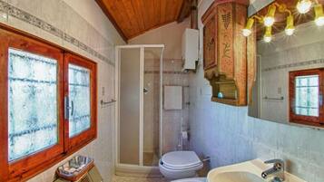 Une salle de bain avec une fenêtre à cadre en bois, une douche en verre et un lavabo avec un miroir.