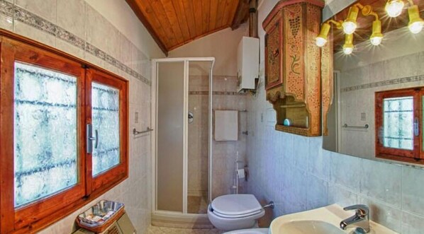 A bathroom with a wooden-framed window, a glass-enclosed shower, and a sink with a mirror.