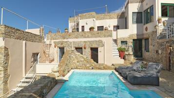 Een buitenzwembad, parasols bij het zwembad en ligstoelen