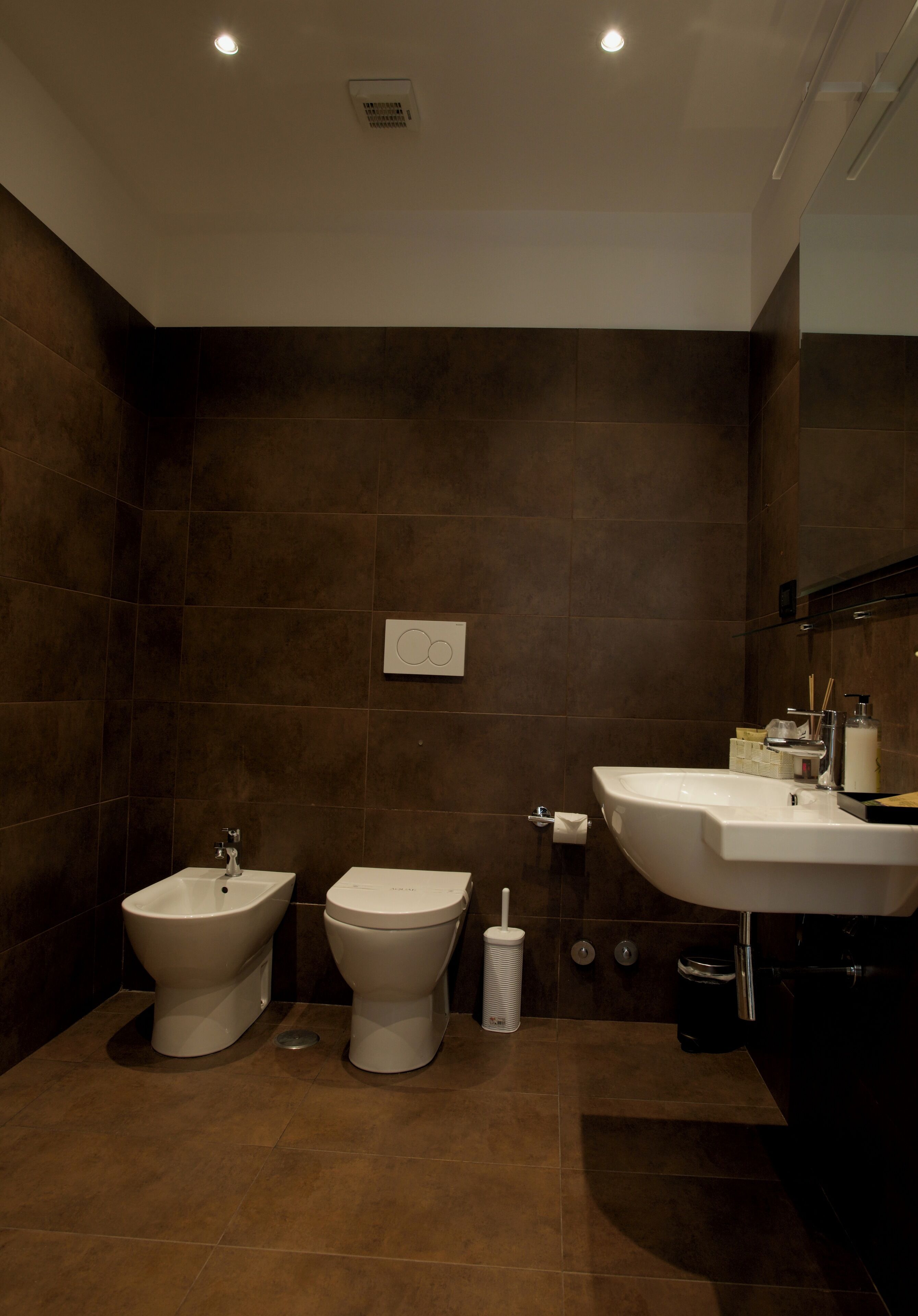 Ein modernes Badezimmer mit zwei Toiletten, einem Waschbecken und einem Spiegel.
