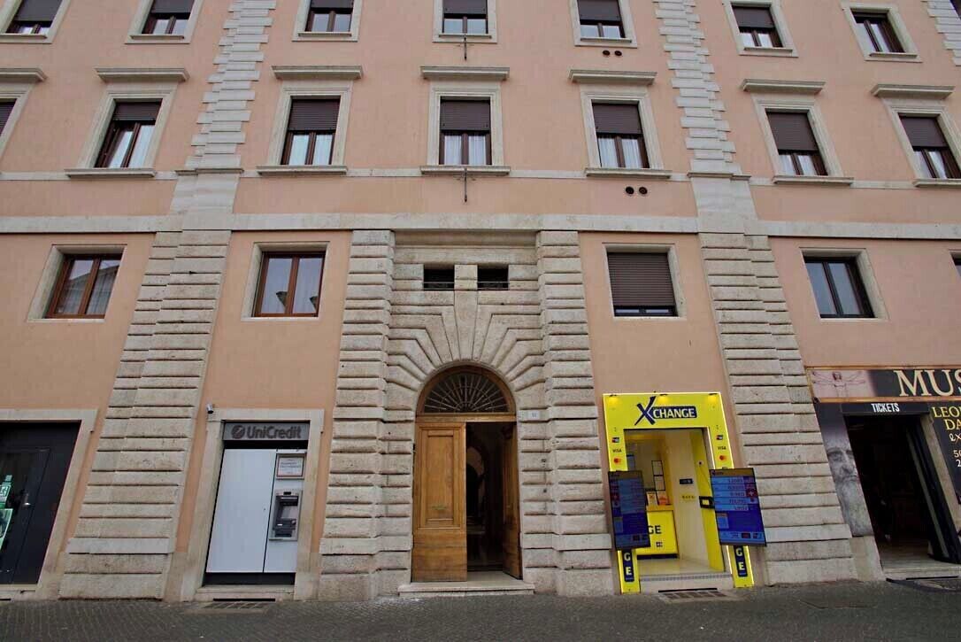 A multi-story building with a central entrance, a UniCredit ATM, and a yellow XCHANGE currency exchange booth.