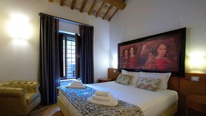 Een hotelkamer met een groot bed, een hoofdeinde met kunstwerk, een bank en een raam met gordijnen.