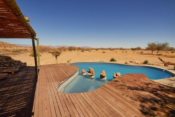 Una piscina al aire libre, sombrillas, tumbonas